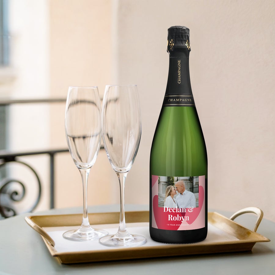 A bottle of champagne with personalised label featuring a couple's photo and the names Declan & Robyn