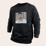 A black personal sweater with a printed photo of a man smiling against a wooden background