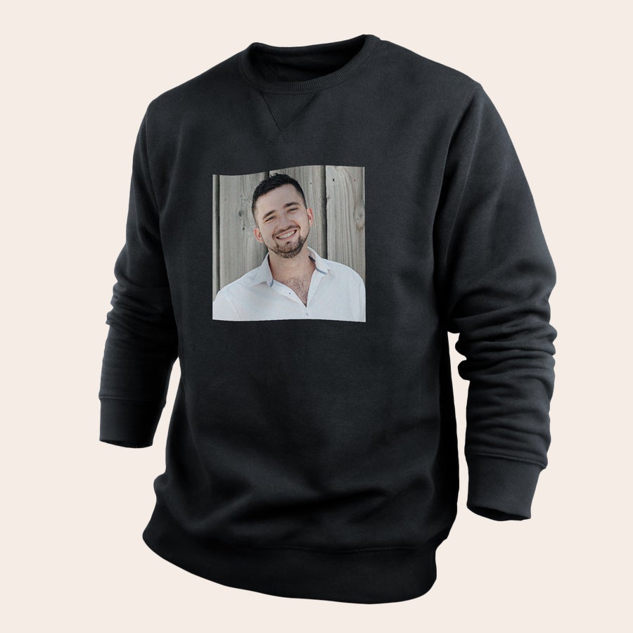 A black personal sweater with a printed photo of a man smiling against a wooden background