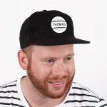 Black baseball cap printed with a white circle and the name THOMAS, worn by a man.