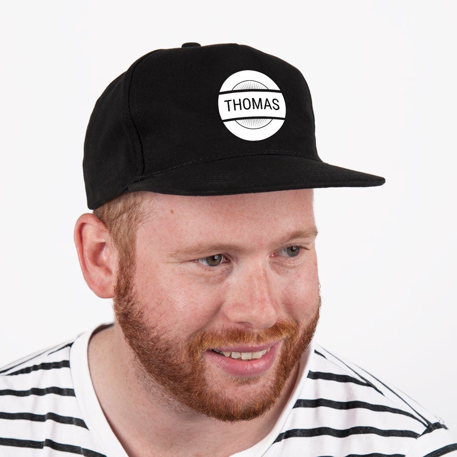 Black baseball cap printed with a white circle and the name THOMAS, worn by a man.