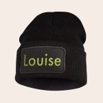 Black beanie with a personalized embroidered name Louise in green text on the front to keep ears warm