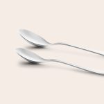 Two shiny stainless steel spoons, ready to be engraved with a personalized name for a unique children's cutlery set