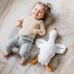 Personalised cuddly toy goose with embroidered name Charlotte and date 03-06-2022 next to a baby