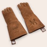Two personalized brown leather BBQ gloves, one engraved with a name, the other with Dad and a name.
