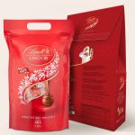 A 1 kg bag of Lindor milk chocolate truffles inside a personalized gift box. The red box features a design that can be customized with a photo, name, and text.