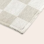 A close-up of a white textured Personalised play mat - 75 x 122 cm, showing its corner and woven details.