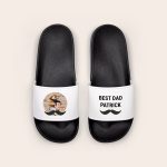 White personalised sliders with black soles. One slider is printed with a photo of a man and child and a black mustache graphic. The other slider is printed with the text BEST DAD PATRICK and a black mustache graphic.