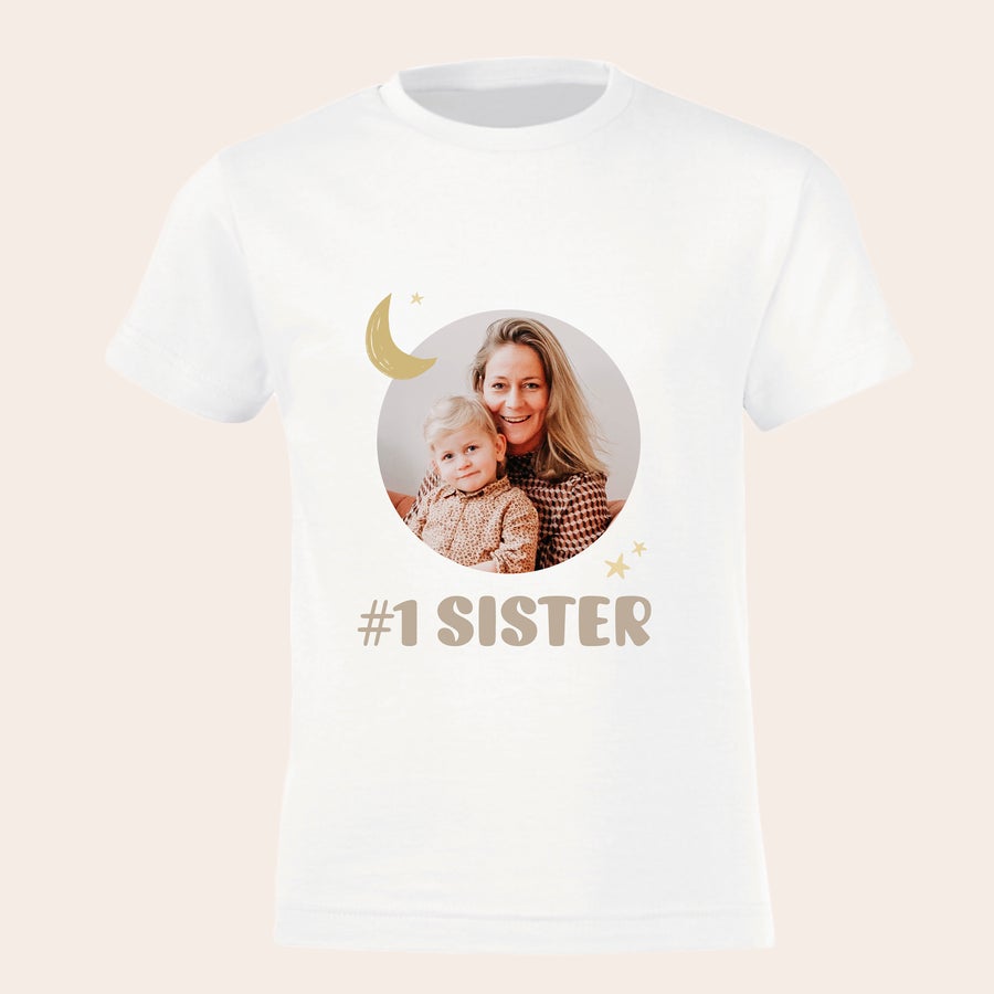 White t-shirt for pregnancy announcement, printed with a photo of a mother and child, and #1 Sister text