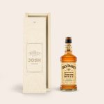 A bottle of Jack Daniels Honey whisky next to an engraved wooden case with the name JOSH