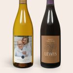 Two bottles of wine, one with a photo of a couple printed on a personal label, and another with a customized Lewis vineyard label.