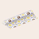 Personalised wrapping paper printed with a childs photo in a daisy pattern and yellow smiley faces on a lilac background.