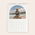 Personalised 2026 calendar with a child on an adults shoulders at the beach, printed on the January page