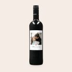 A bottle of Maison de la Surprise Merlot with a personalized label, printed with a photo of a couple and the text Matthew & Emily 12.02.2022 to surprise your loved ones.
