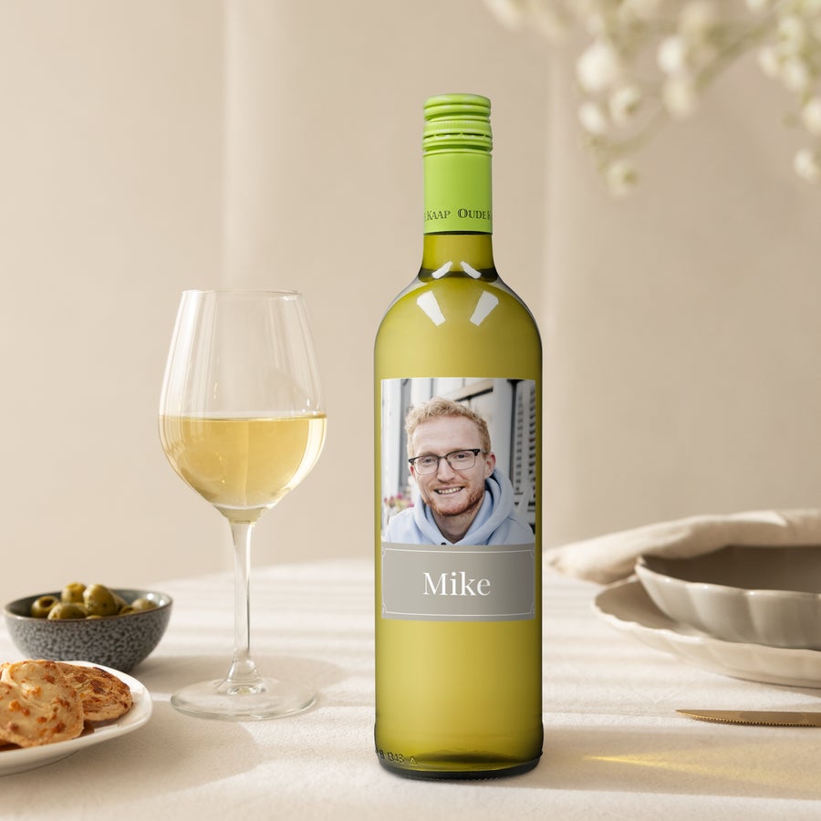 Oude Kaap white wine bottle with a personalized photo label and the name Mike printed on it, next to a wine glass.