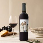 Riondo Merlot wine bottle with a personalized label, printed with a photo of a couple, next to a wine glass