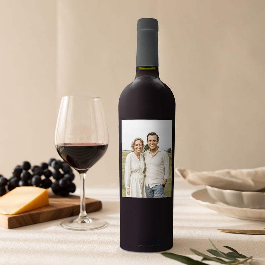 Riondo Merlot wine bottle with a personalized label, printed with a photo of a couple, next to a wine glass