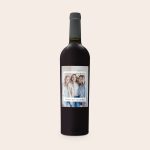 A bottle of Riondo Merlot wine with a personalized label, printed with a photo of three smiling women and the text Cheers to Friendship.